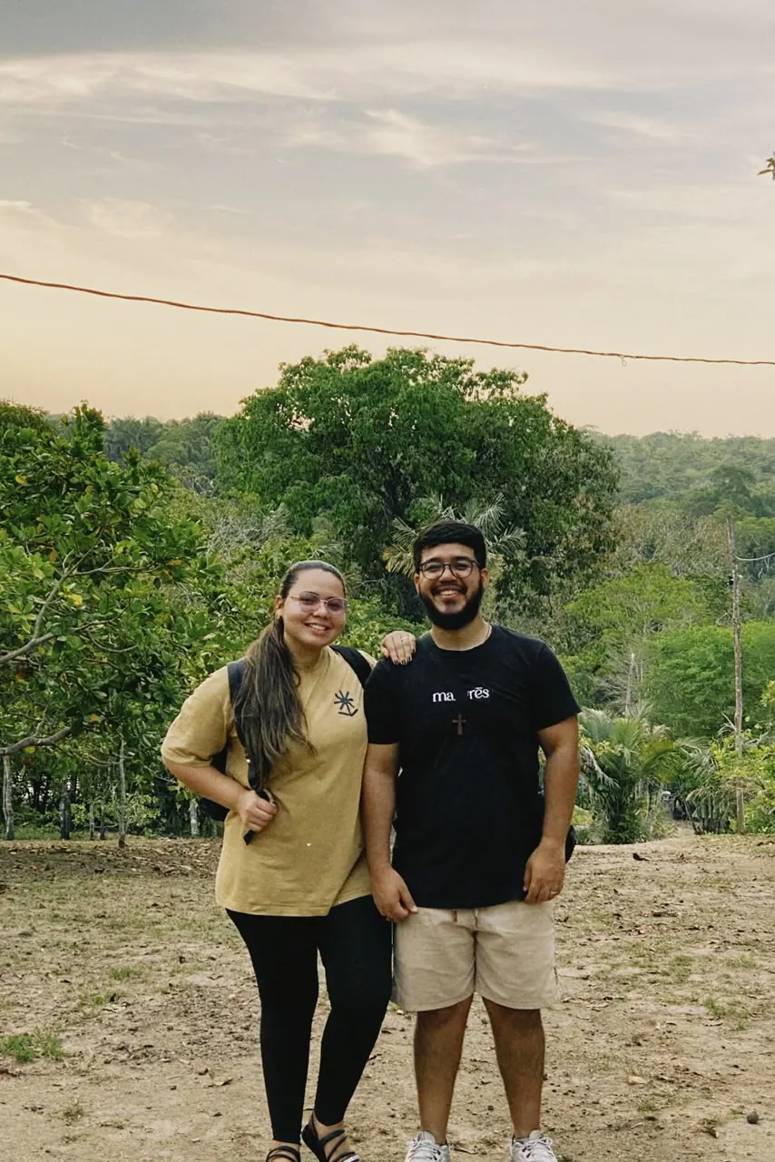 Diego e Nathália sorrindo, lado a lado, em meio às árvores